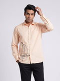 Man wearing a peach sailor shirt by BUNO with an embroidered ship paired with black pants.
