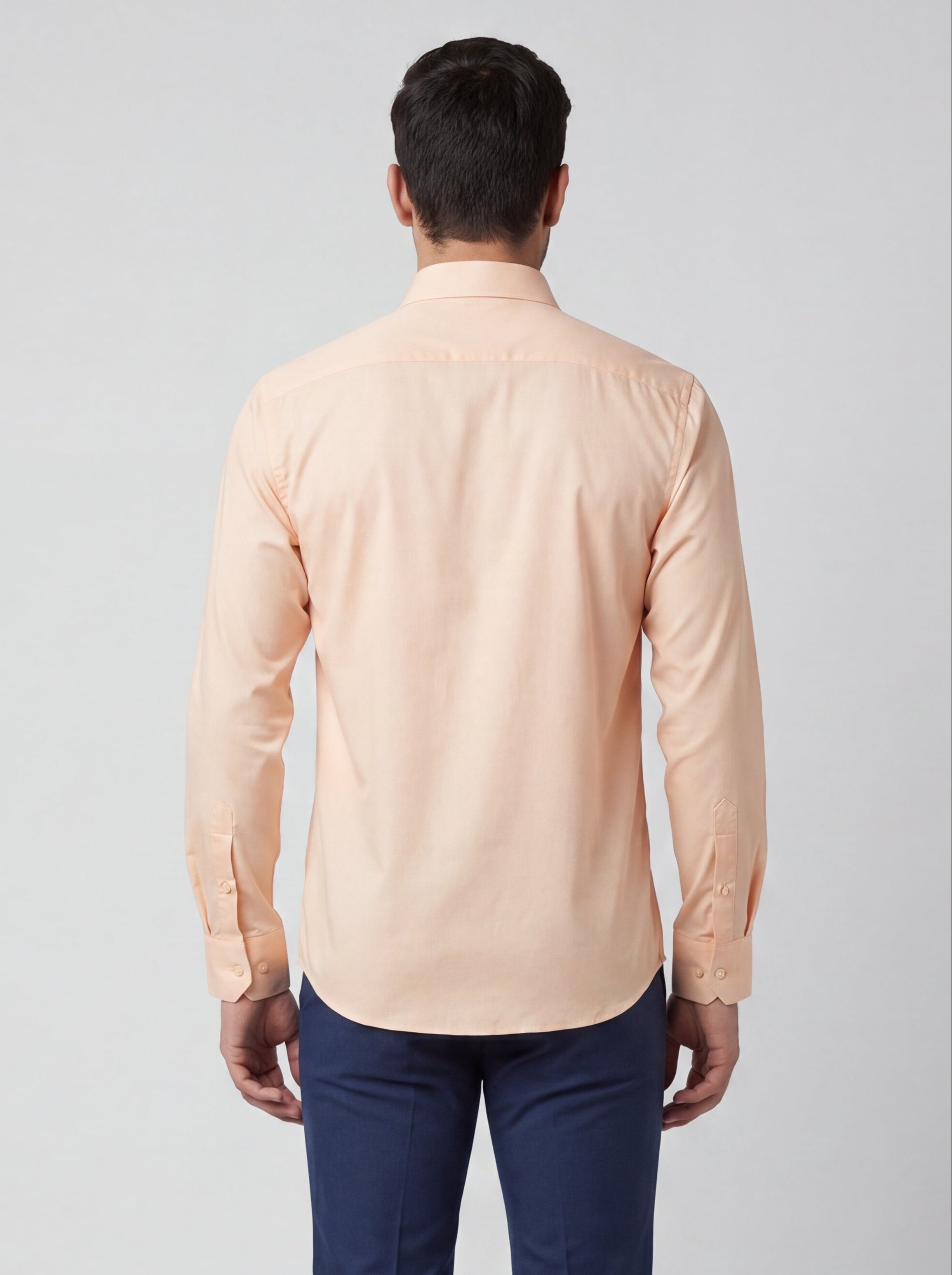 Man wearing a peach shirt and blue pants on a white background